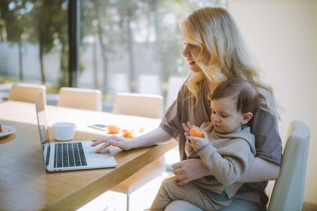 Mom with child on lap working from home on her laptop